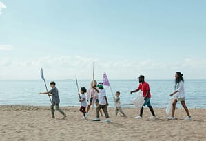 Un grupo de personas caminando por una playa con banderas ecológicas, abrazando un estilo de vida que promueve la conciencia ambiental.